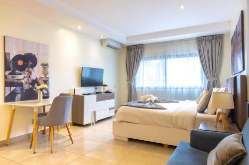 a bedroom with a bed and a desk with a computer at CasaNova Airport Suites in Accra