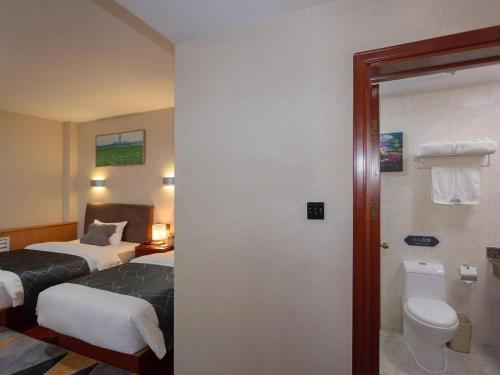 a hotel room with two beds and a toilet at Chonpines Hotel Jining Quanmin Fitness Plaza in Jining