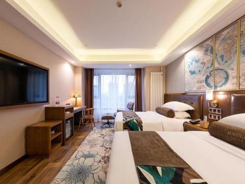 a hotel room with two beds and a flat screen tv at James Joyce Coffetel Harbin West High-speed Railway Station Wanda Plaza in Harbin