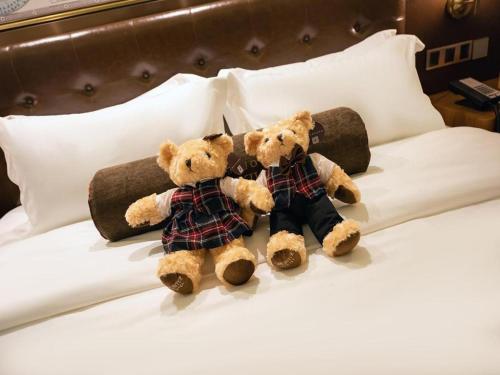 two teddy bears are sitting on a bed at James Joyce Coffetel Harbin West High-speed Railway Station Wanda Plaza in Harbin
