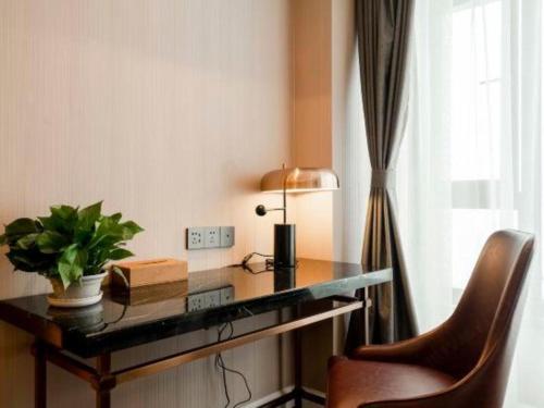 a desk with a lamp and a plant on it at James Joyce Coffetel Harbin West High-speed Railway Station Wanda Plaza in Harbin