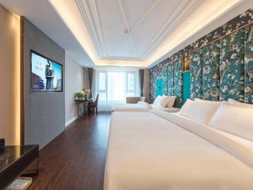 a hotel room with a large bed and a tv at James Joyce Coffetel Harbin West High-speed Railway Station Wanda Plaza in Harbin