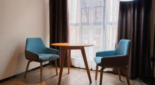 two chairs and a table in front of a window at City Comfort Inn Kunming High Speed Railway South Station Yongxin Harvard in Kunming