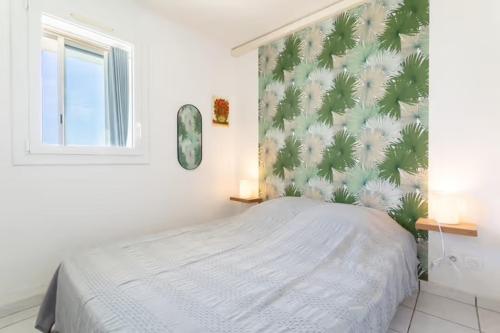 une chambre avec un lit avec un papier peint tropical dans l'établissement Canet plage face à la mer, à Canet