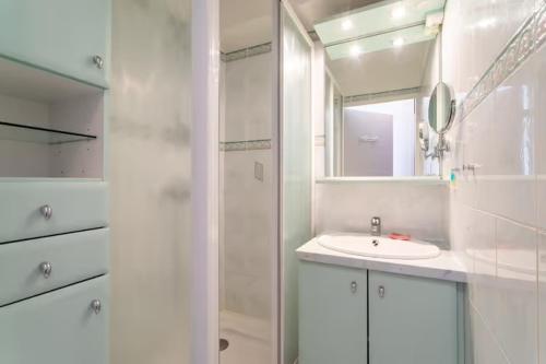 une salle de bain blanche avec un lavabo et un miroir dans l'établissement Canet plage face à la mer, à Canet