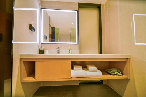 een badkamer met een wastafel, een spiegel en handdoeken bij City Comfort Inn Zhaoqing Sihui Nanjiang Industrial Park in Xiahuangtang
