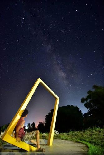 a man sitting in a yellow pyramid with a mirror at 三仙台星辰民宿 in Chenggong