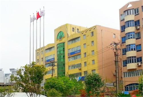 a yellow building with flags in front of it at 7Days Inn Changshou Road Subway station in Shanghai