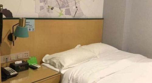 a bedroom with a bed and a desk with a phone at Vatica Hotel Hefei Yaohai Longgang Subway Station in Hefei