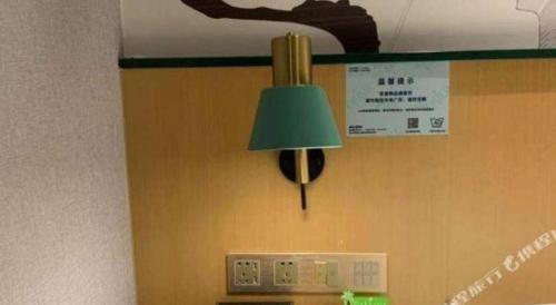 a green lamp hanging on a wall next to an appliance at Vatica Hotel Hefei Yaohai Longgang Subway Station in Hefei