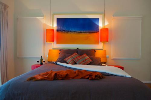 a bedroom with a bed with a painting on the wall at Wilderberry Cottage in Berry
