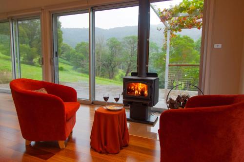 a living room with two chairs and a wood stove at Wilderberry Cottage in Berry