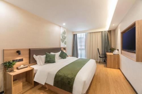 a hotel room with a large bed and a television at GreenTree Inn Express Zhangjiagang Hexing Town Shazhou Professional Institue of Technology in Qiwei