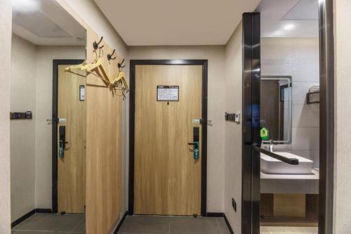 a bathroom with two wooden doors and a sink at GreenTree Inn Express Zhangjiagang Hexing Town Shazhou Professional Institue of Technology in Qiwei