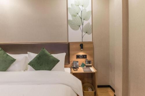a bedroom with a bed and a table with a telephone at GreenTree Inn Express Zhangjiagang Hexing Town Shazhou Professional Institue of Technology in Qiwei