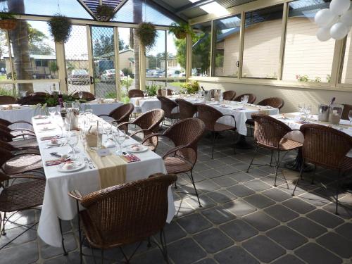 a dining room with white tables and chairs at Amaroo Resort in Sussex inlet