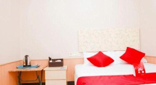 a bedroom with a bed with red pillows and a desk at OYO Huifeng Business Hotel in Lanzhou