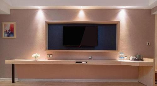 a living room with a flat screen tv on a wall at Borrman Hotel Liuzhou High-Speed Railway Station in Liuzhou