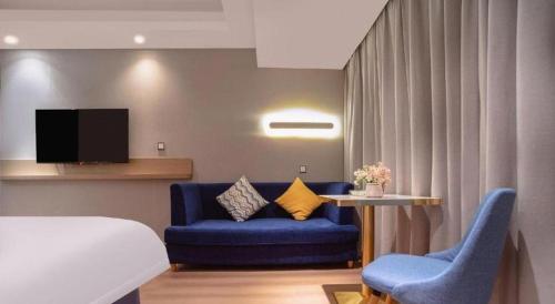 a hotel room with a bed and a couch and a table at Borrman Hotel Liuzhou High-Speed Railway Station in Liuzhou