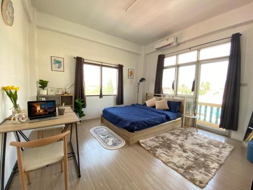 a bedroom with a bed and a desk with a laptop at Cozy Room Near Mahidol University For International Students in Sathani Sala Ya