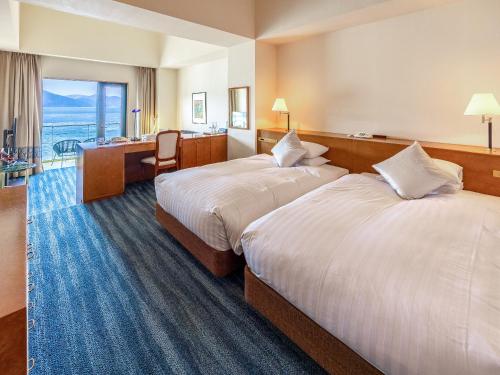 a hotel room with two beds and a desk at Hakone Hotel in Hakone