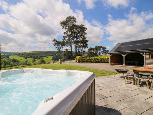 a large hot tub on a patio with a table and a picnic table at The Hayloft in Knighton