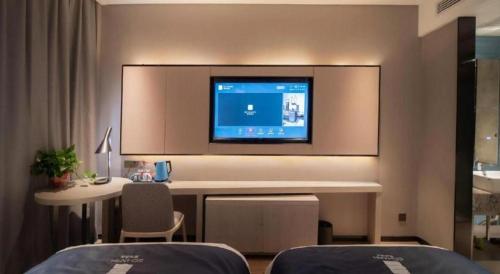 a room with a desk and a tv on the wall at Echarm Hotel Changsha Wuyi Square Xiangya Affiliated 1st Provincial Maternity and Child in Changsha