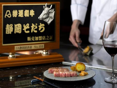 a table with a plate of meat and a glass of wine at Hakone Hotel in Hakone