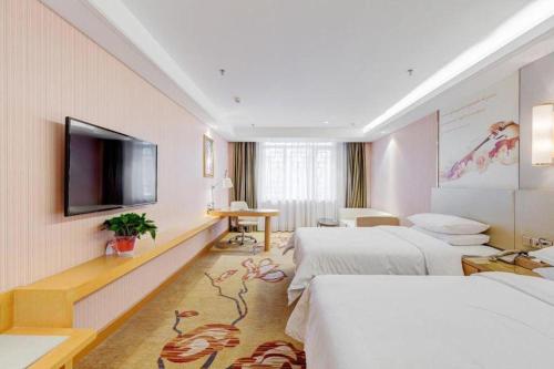 a hotel room with two beds and a flat screen tv at Vienna Hotel Shandong Qufu Sankong Landscape in Jining