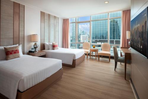 a hotel room with two beds and a desk at The Berkeley Hotel Pratunam in Bangkok