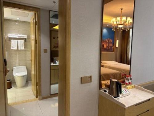 ein Badezimmer mit einem Bett, einem Waschbecken und einem Spiegel in der Unterkunft Vienna Hotel Shandong Yuncheng Shuihu Road Hoahancheng in Yuncheng