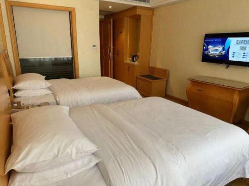 a hotel room with two beds and a flat screen tv at Vienna Hotel Guangdong Zhaoqing Sihui Tianguangxu in Zhaoqing