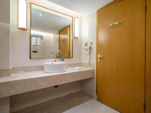 a bathroom with a sink and a mirror at Vienna Hotel Fuzhou Changle Shouzhan Hangcheng Metro Station in Fuzhou