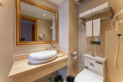 a bathroom with a sink and a mirror and a toilet at Vienna Hotel Hubei Xiaogan Beijing Road in Xiaogan
