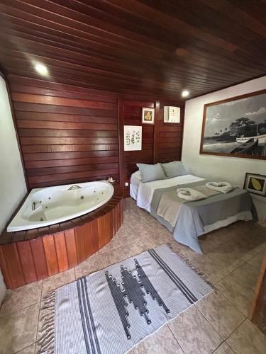a bathroom with a tub and a bed and a bed and a bath tub at Canoa Ilha Grande in Abraão
