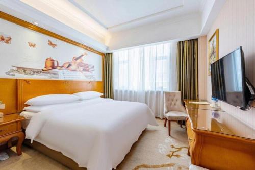 a bedroom with a large white bed and a flat screen tv at Vienna Hotel Hebei Hengshui High-Speed Railway Station in Hengshui