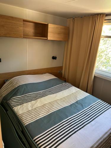 un lit dans une petite pièce avec une fenêtre dans l'établissement Mobilhome Mimizan Plage, à Mimizan
