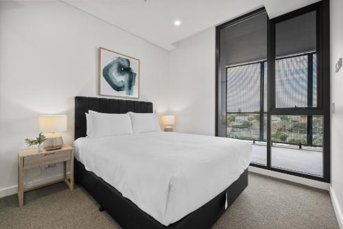 une chambre avec un grand lit blanc et deux fenêtres dans l'établissement Chic 1-Bed Escape in Fremantle with Parking, à North Fremantle