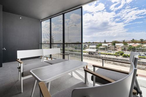 a dining room with a table and chairs and a large window at Chic 1-Bed Escape in Fremantle with Parking in North Fremantle