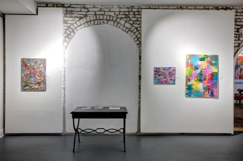 a table in front of a wall with three paintings at La Galerie French Quarter Hotel in New Orleans
