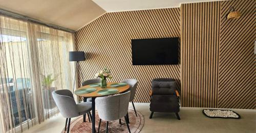 a dining room with a table and chairs and a television at Hétvezér Penthouse Apartments in Szeged