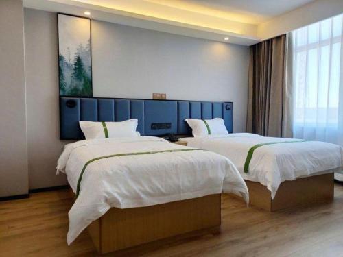 a bedroom with two beds and a painting on the wall at GreenTree Inn Express Qingdao Jiaodong International Airport in Qingdao