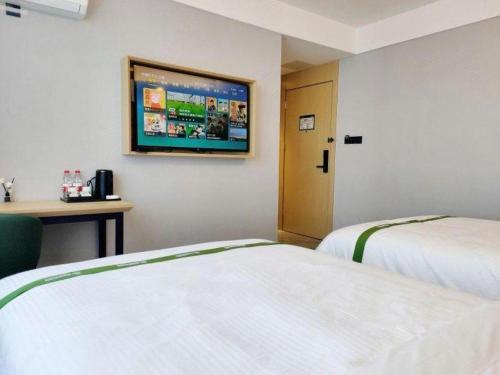 a hotel room with two beds and a flat screen tv at GreenTree Inn Express Qingdao Jiaodong International Airport in Qingdao