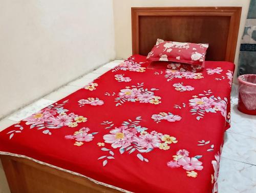 a bed with a red bedspread with flowers on it at Hotel Guest House Saydabad in Dhaka