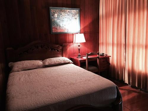 a bedroom with a bed and a table with a lamp at Casa Hotel Sura in San José