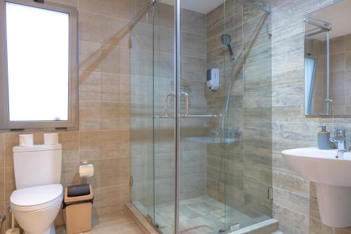 a bathroom with a shower and a toilet and a sink at CasaNova Airport Suites in Accra