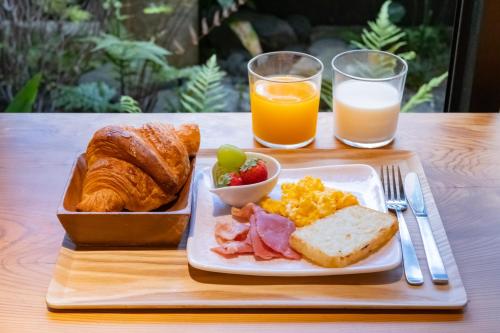 a plate of breakfast food with bread and orange juice at Hotel Ethnography Kiyomizu Gojo in Kyoto