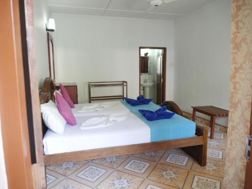 a bedroom with a white bed with purple pillows at Ocean View tourist guest house at Negombo beach near the airport in Negombo