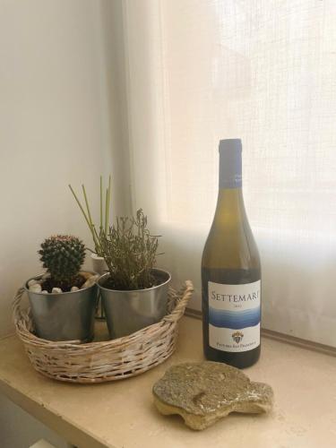 a bottle of wine sitting next to a basket of plants at SoverHouse affittacamere a Soverato Marina in Soverato Marina