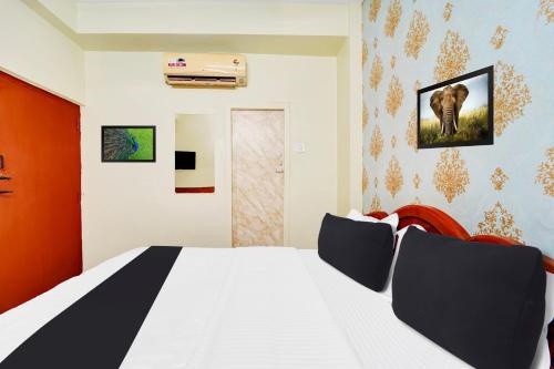 a bedroom with a white bed with an elephant on the wall at Super Hotel O Erode Bus Stand in Erode
